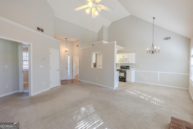 unfurnished living room featuring high vaulted ceiling, light colored carpet, and ceiling fan with notable chandelier