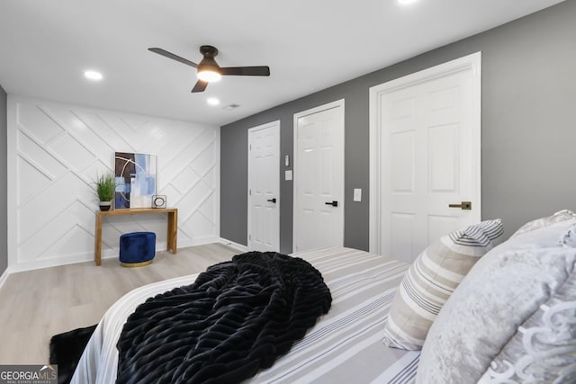 bedroom featuring ceiling fan, two closets, and light hardwood / wood-style floors