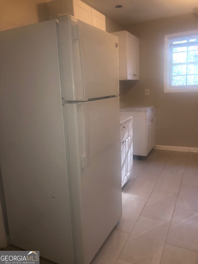 kitchen featuring light tile patterned flooring, white refrigerator, and white cabinets