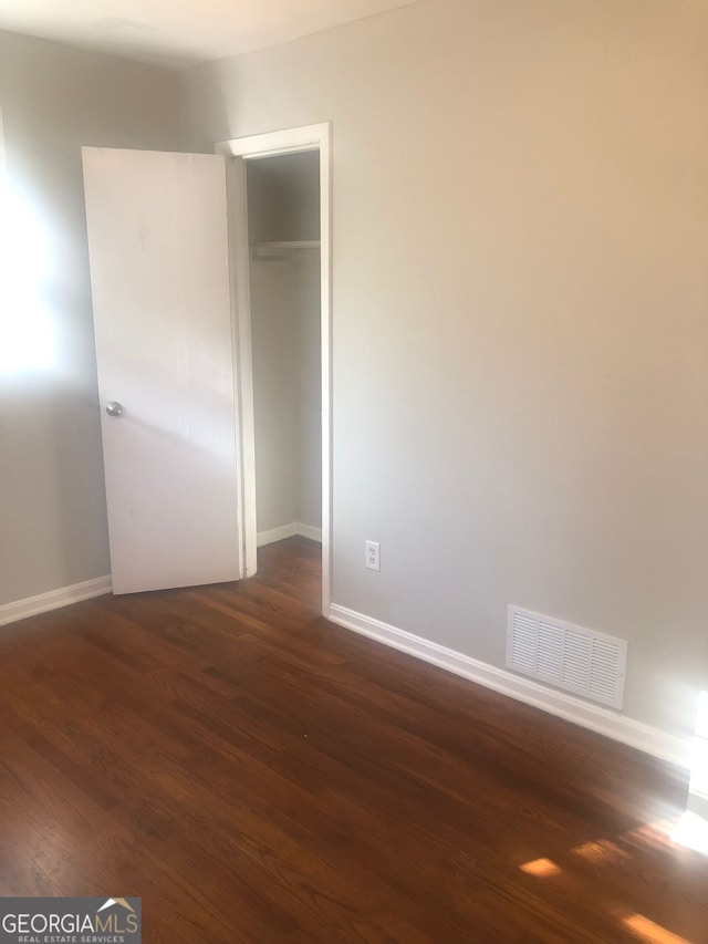 unfurnished bedroom with dark hardwood / wood-style floors and a closet