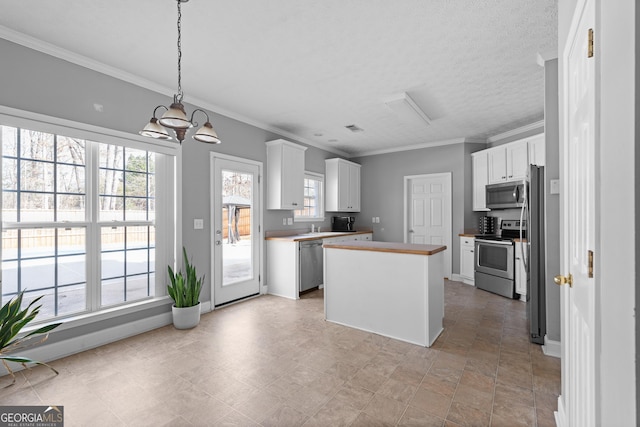 kitchen featuring a kitchen island, white cabinetry, butcher block counters, stainless steel appliances, and a notable chandelier