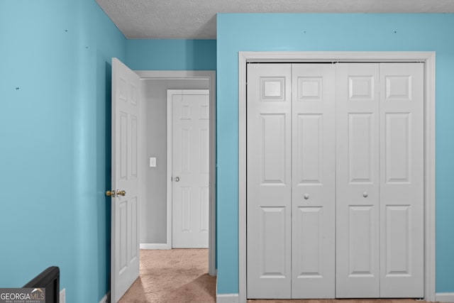 unfurnished bedroom with light carpet, a closet, and a textured ceiling