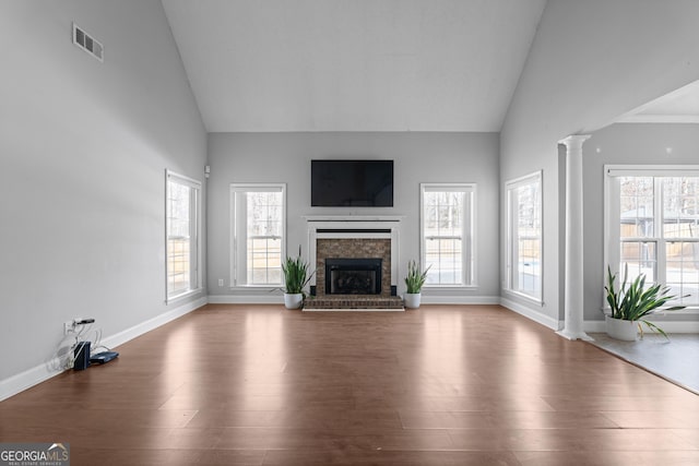 unfurnished living room with a wealth of natural light, ornate columns, and a fireplace