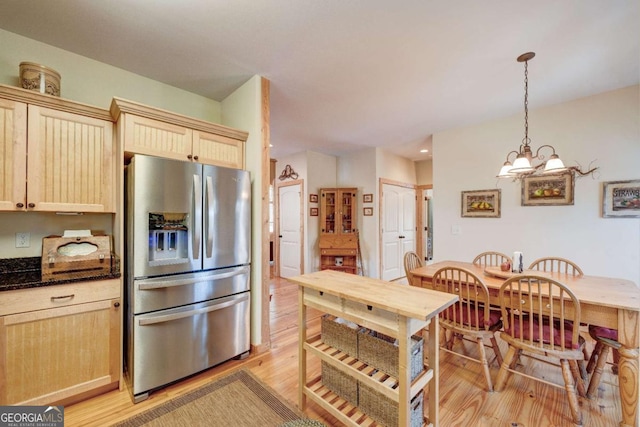 kitchen featuring stainless steel fridge with ice dispenser, pendant lighting, light brown cabinets, and a notable chandelier