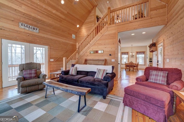 living room featuring high vaulted ceiling, a wealth of natural light, and wooden walls