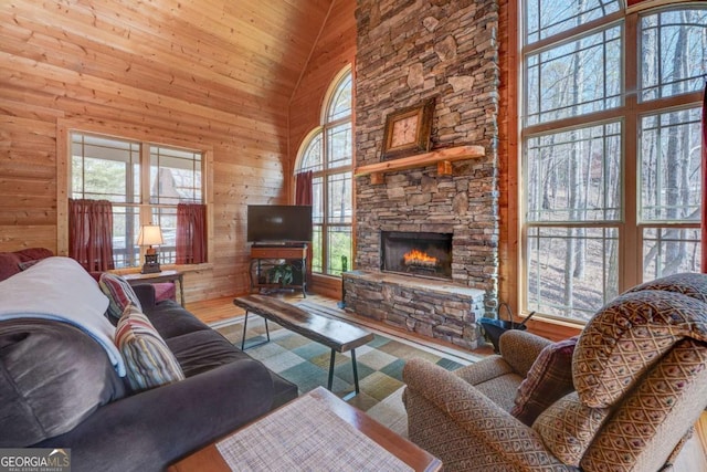 living room with a healthy amount of sunlight, a fireplace, hardwood / wood-style flooring, and high vaulted ceiling