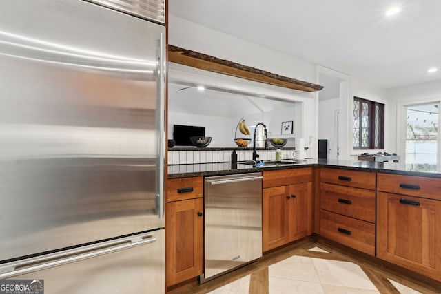 kitchen featuring dark stone counters, sink, and stainless steel appliances