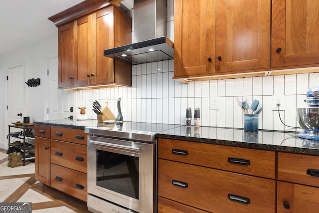 kitchen with stainless steel range with electric stovetop, light tile patterned floors, backsplash, dark stone counters, and wall chimney range hood