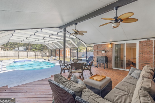 view of pool featuring a wooden deck, outdoor lounge area, and glass enclosure