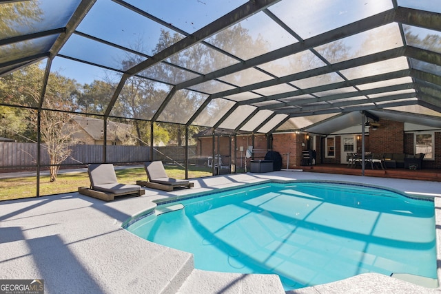 view of swimming pool with ceiling fan, glass enclosure, and a patio