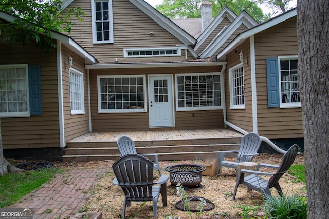 back of house featuring a deck and a fire pit