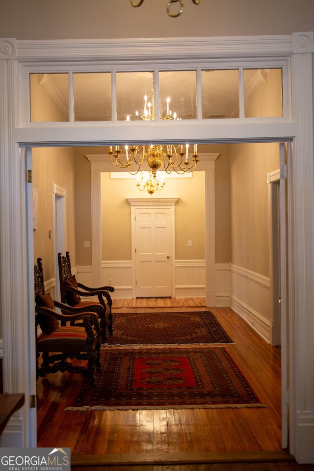 interior space featuring an inviting chandelier, ornamental molding, and hardwood / wood-style floors