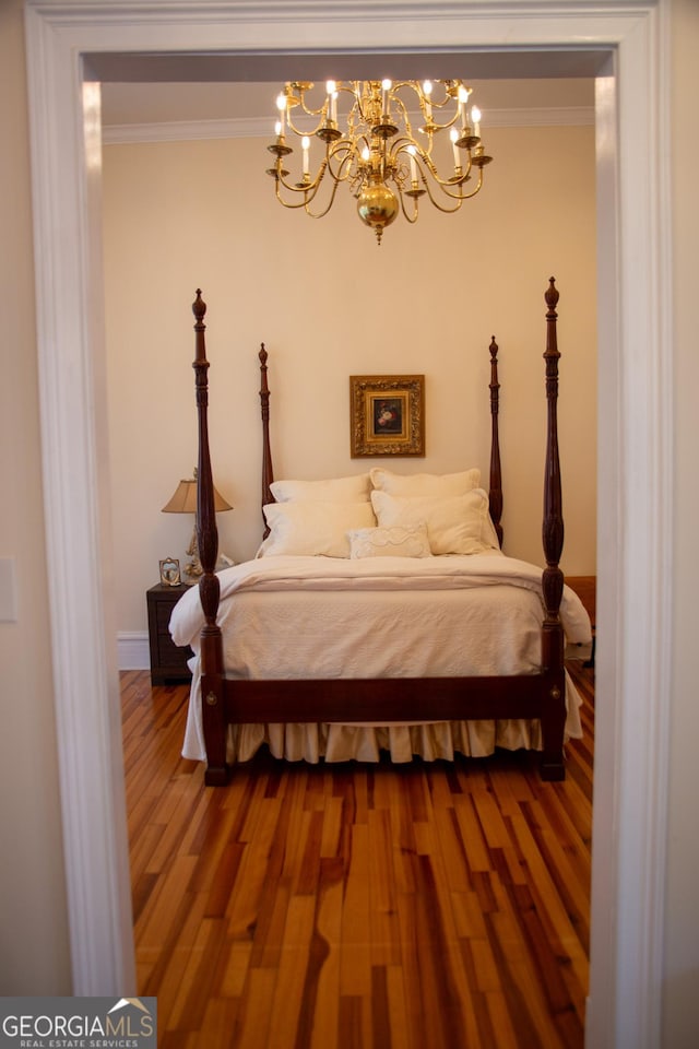 bedroom featuring crown molding, wood-type flooring, and a notable chandelier