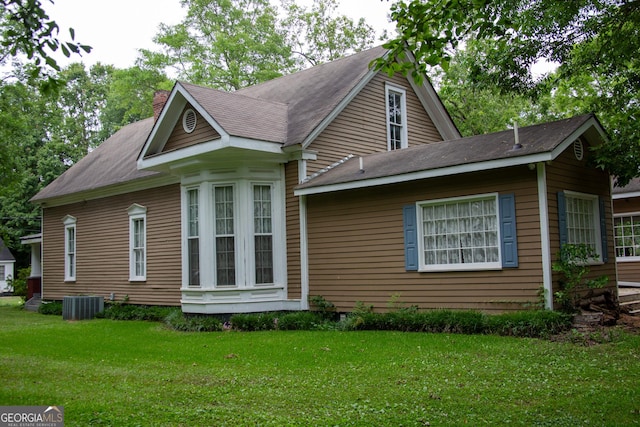 view of side of property with central AC unit and a yard