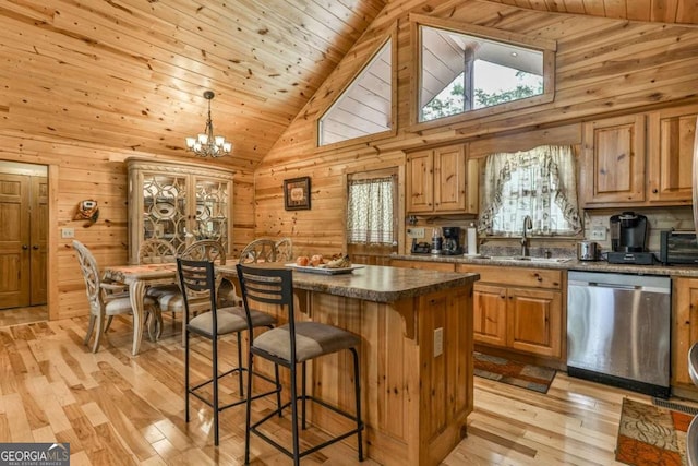 kitchen with a kitchen island, stainless steel dishwasher, sink, hanging light fixtures, and light wood-type flooring