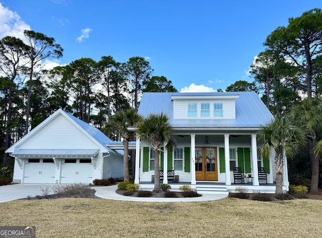 view of front of house featuring french doors, a garage, covered porch, and a front lawn