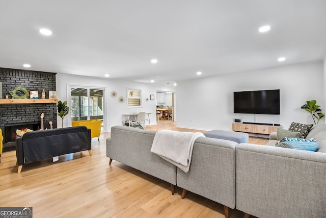 living room featuring a brick fireplace and light hardwood / wood-style floors