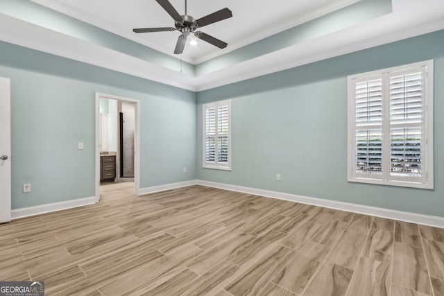 empty room featuring a tray ceiling, a ceiling fan, baseboards, visible vents, and light wood-style floors