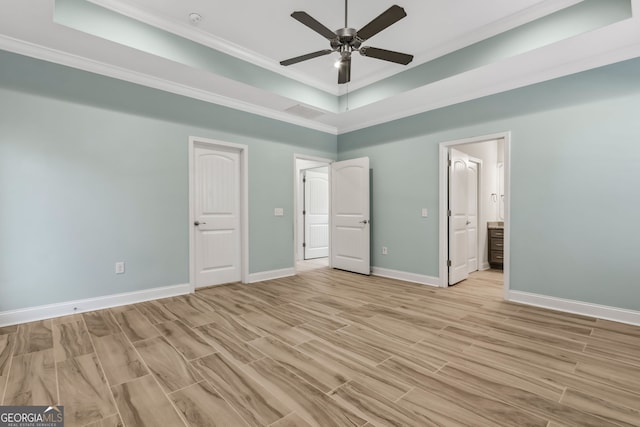empty room with baseboards, light wood-style flooring, a ceiling fan, and a raised ceiling