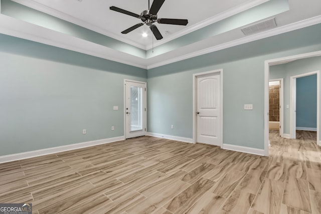 unfurnished bedroom with baseboards, connected bathroom, ornamental molding, light wood-style floors, and a tray ceiling