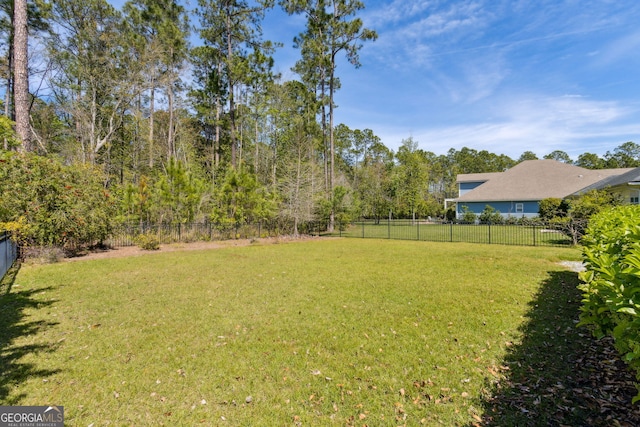 rear view of property featuring roof with shingles, a sunroom, fence, and a yard