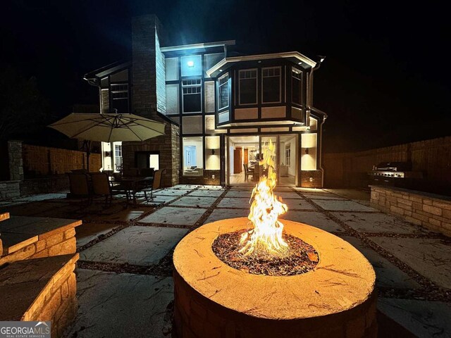 back house at night with a patio area and a fire pit