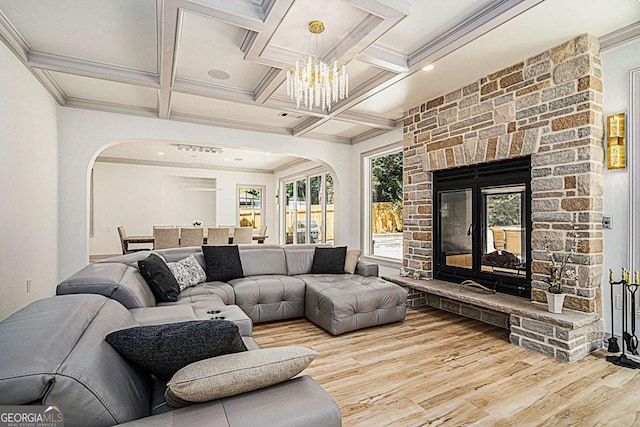 living room with hardwood / wood-style flooring, coffered ceiling, a stone fireplace, and beamed ceiling