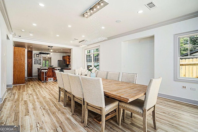 dining area with light wood-type flooring and ornamental molding