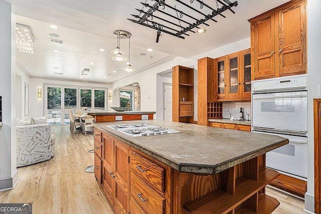 kitchen with a center island, double oven, tasteful backsplash, light hardwood / wood-style floors, and stainless steel gas stovetop