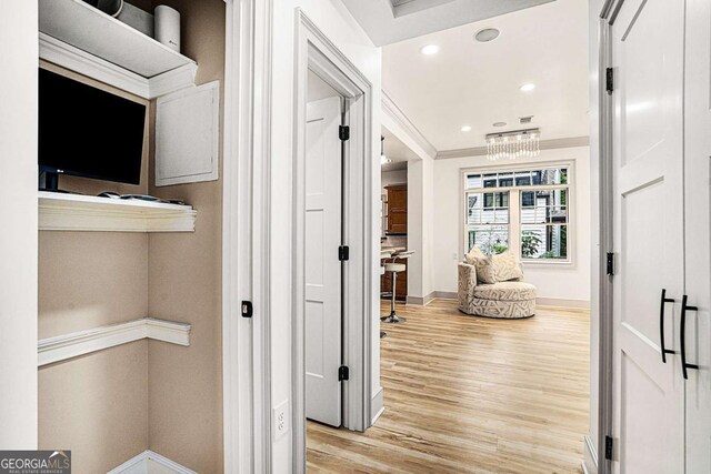 hallway with crown molding and light hardwood / wood-style floors