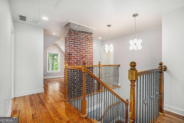 corridor with wood-type flooring and a notable chandelier