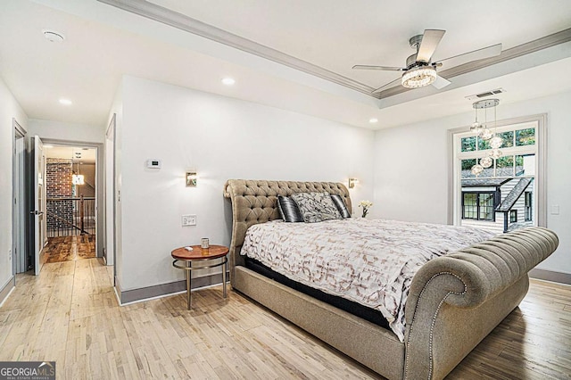 bedroom with light wood-type flooring, ceiling fan, crown molding, and a raised ceiling