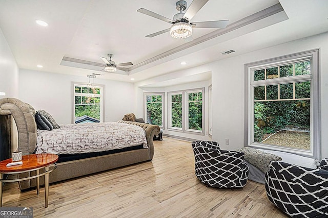 bedroom with a raised ceiling, ceiling fan, light wood-type flooring, and crown molding