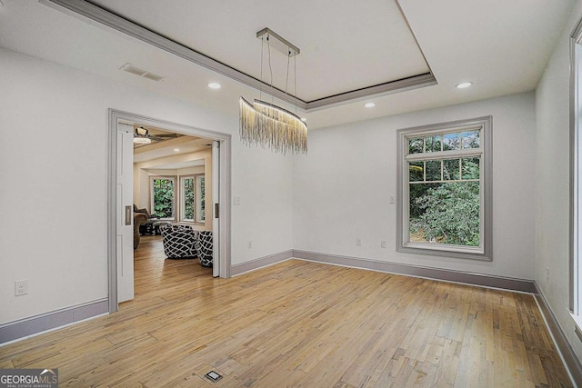 unfurnished room with ceiling fan, light hardwood / wood-style floors, plenty of natural light, and a tray ceiling