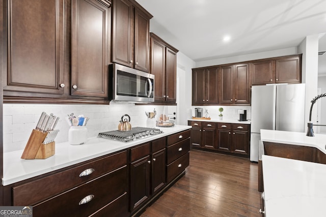 kitchen with appliances with stainless steel finishes, dark brown cabinetry, and dark hardwood / wood-style floors