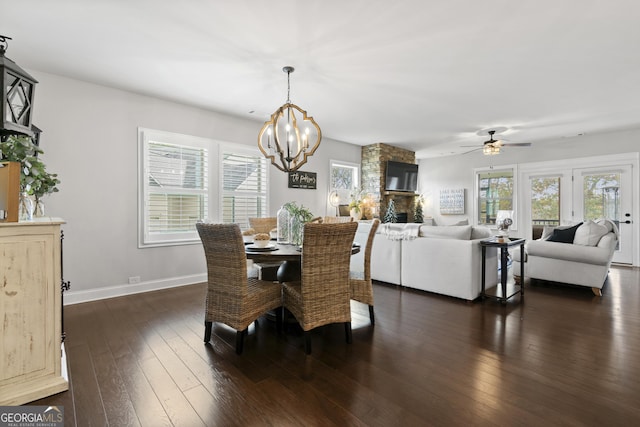 dining space with ceiling fan with notable chandelier, a healthy amount of sunlight, and dark hardwood / wood-style flooring