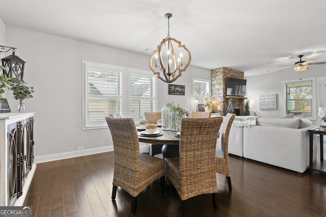 dining room with a fireplace, dark hardwood / wood-style floors, and ceiling fan with notable chandelier