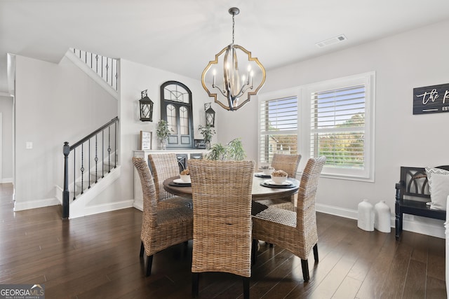 dining space featuring dark wood-type flooring and an inviting chandelier