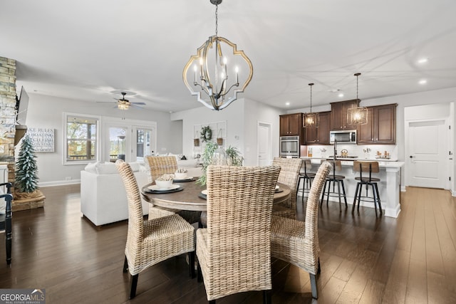 dining room featuring dark hardwood / wood-style flooring, sink, and ceiling fan with notable chandelier