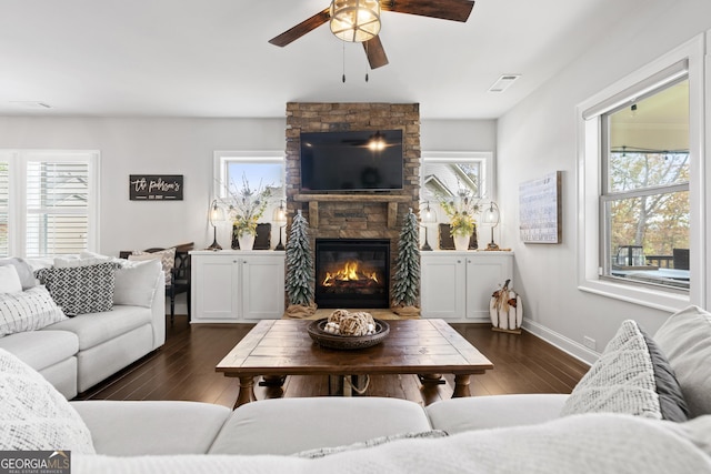 living room featuring a fireplace, dark wood-type flooring, and ceiling fan