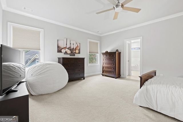 carpeted bedroom with visible vents, crown molding, baseboards, ceiling fan, and ensuite bath