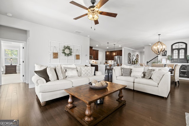 living room featuring ceiling fan with notable chandelier and dark wood-type flooring