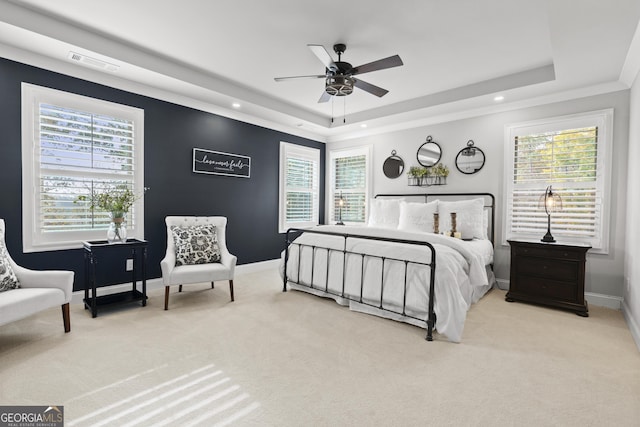 carpeted bedroom with multiple windows, ceiling fan, and a raised ceiling