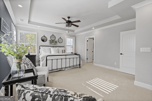 carpeted bedroom with crown molding, a tray ceiling, and ceiling fan