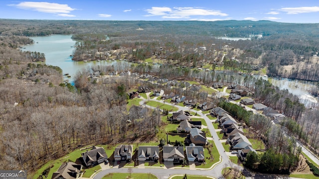 drone / aerial view featuring a wooded view, a water view, and a residential view