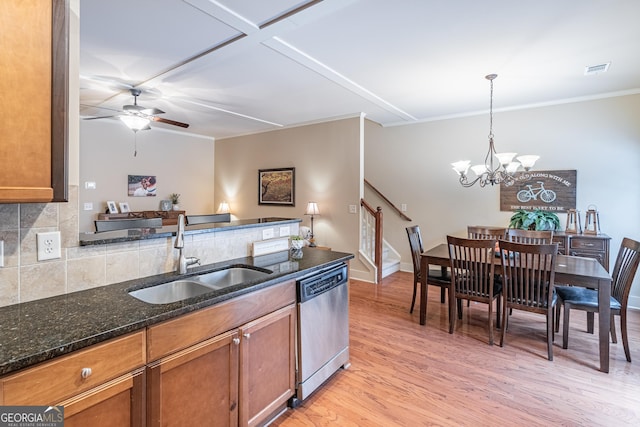 kitchen featuring pendant lighting, sink, dark stone countertops, stainless steel dishwasher, and light hardwood / wood-style floors