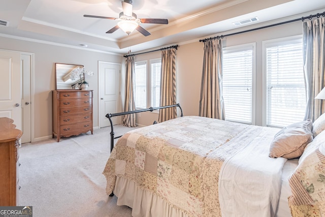 bedroom featuring a raised ceiling, ornamental molding, light colored carpet, and ceiling fan