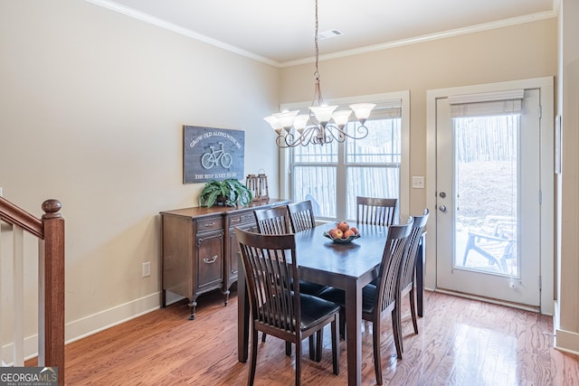 dining room with an inviting chandelier, ornamental molding, and light hardwood / wood-style floors