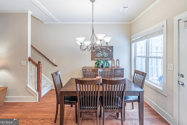 dining area featuring hardwood / wood-style flooring, crown molding, and an inviting chandelier