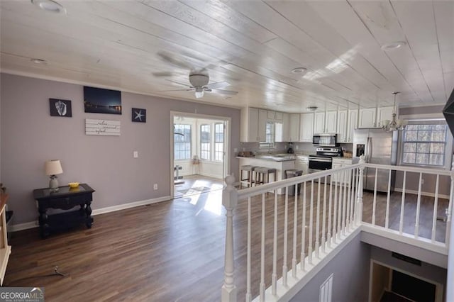 kitchen with ceiling fan with notable chandelier, appliances with stainless steel finishes, white cabinetry, wood-type flooring, and wooden ceiling